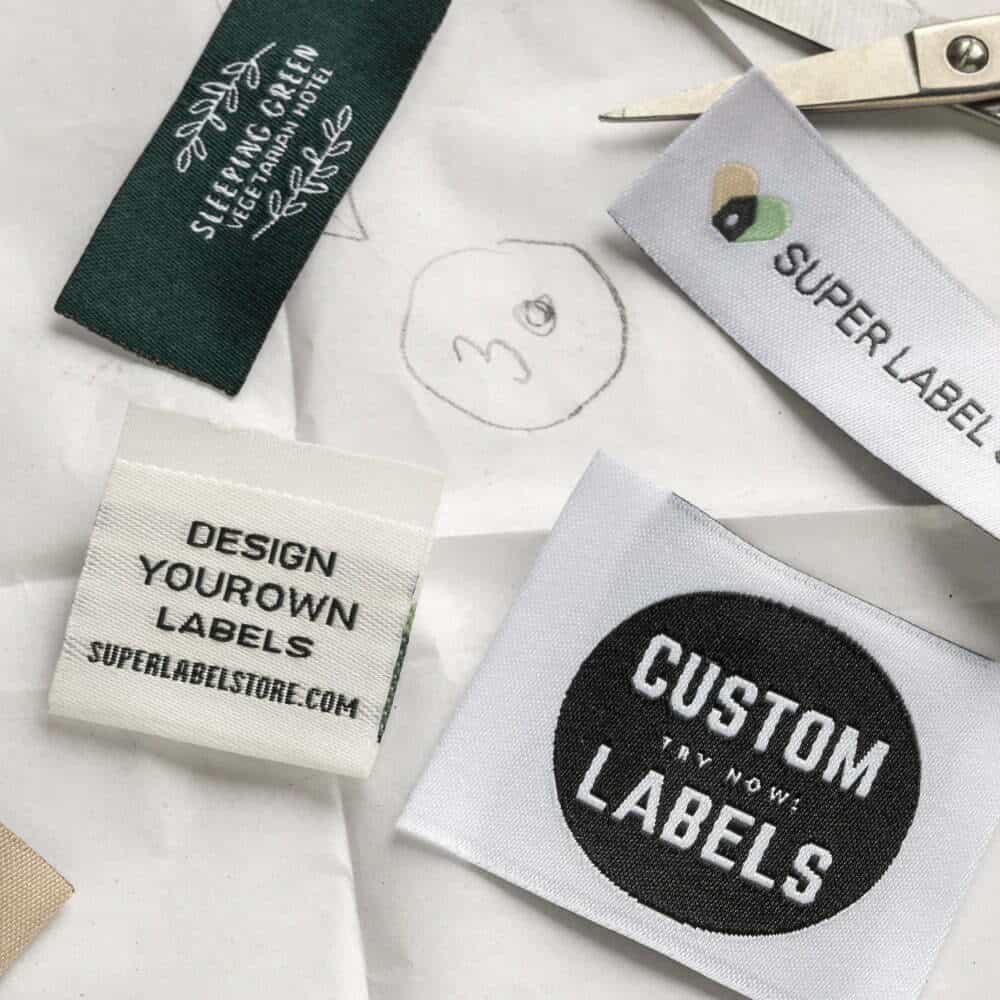 Green and white woven label samples on pattern paper, including a leafy hotel logo and a circular Custom Labels badge.