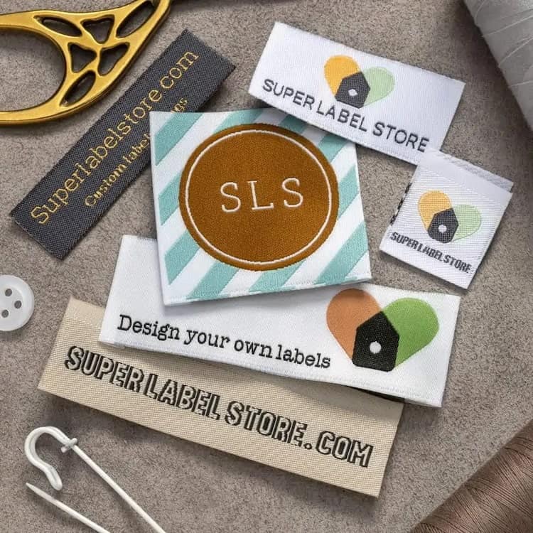 Woven label samples beside sewing tools, centered on a brown SLS circle over mint and white diagonal stripes.