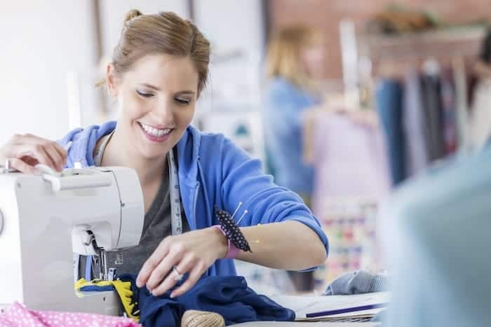 Happy woman uses a sewing machine